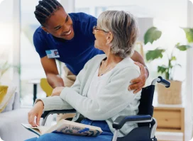 Nurse comforting an elderly woman in a wheelchair.