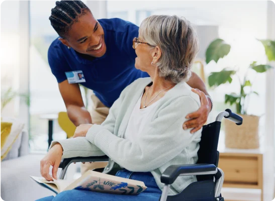 Nurse comforting an elderly woman in a wheelchair.